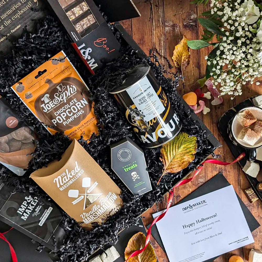 Gourmet gift basket with Halloween-themed items on a wooden surface.
