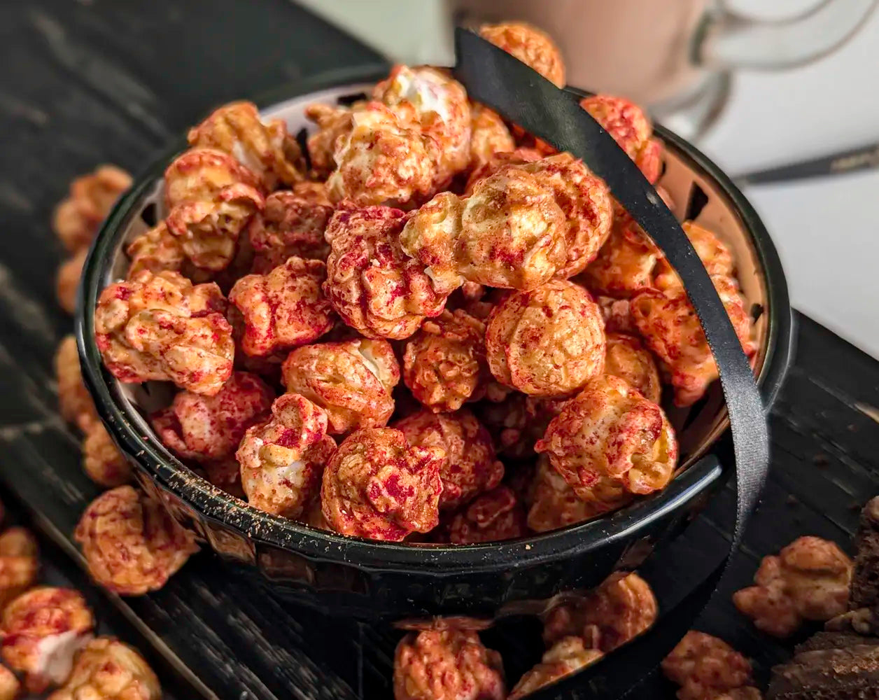 Bowl of popcorn on a black surface with a blurred background