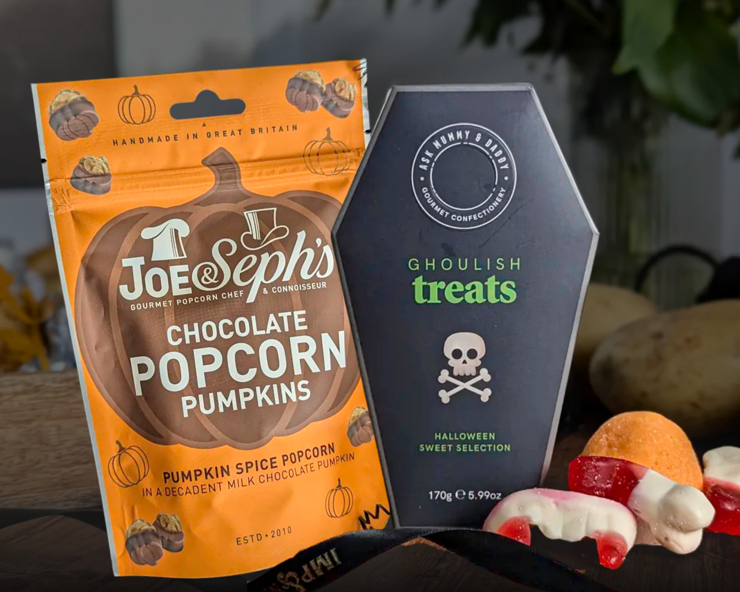 Joe Seph's chocolate popcorn pumpkins packaging and a coffin-shaped bag of 'Ghoulish Treats' on a dark surface.