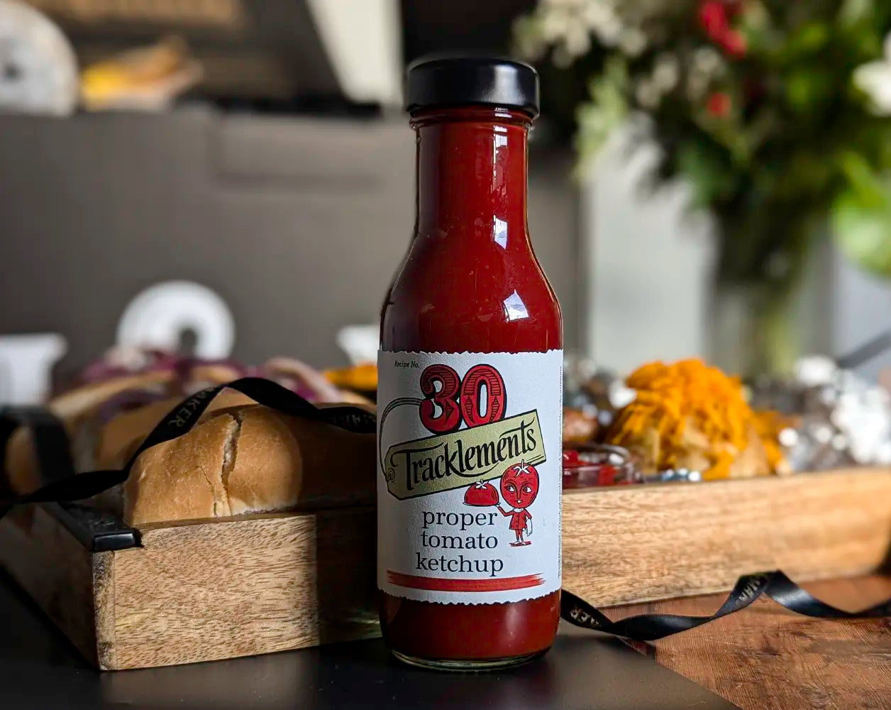 Bottle of Tracklements proper tomato ketchup on a wooden surface with blurred background