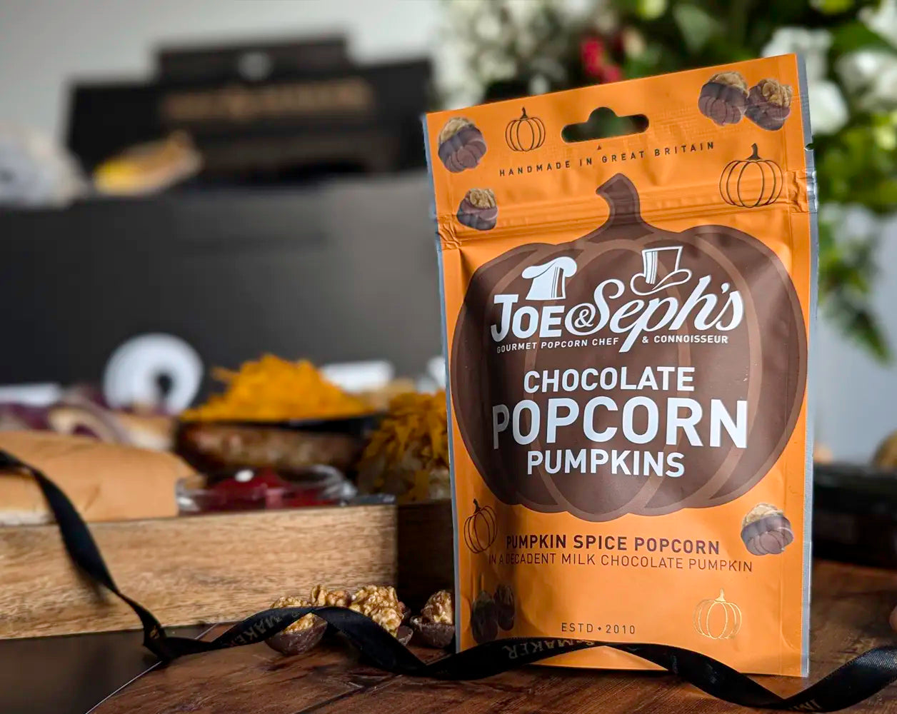 Joe Seph's Chocolate Popcorn Pumpkins packaging on a wooden surface with blurred background