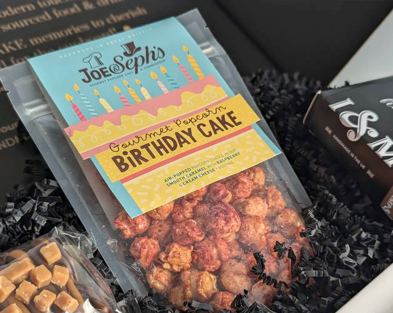 Packaged gourmet popcorn with 'Birthday Cake' flavor in a decorative box.