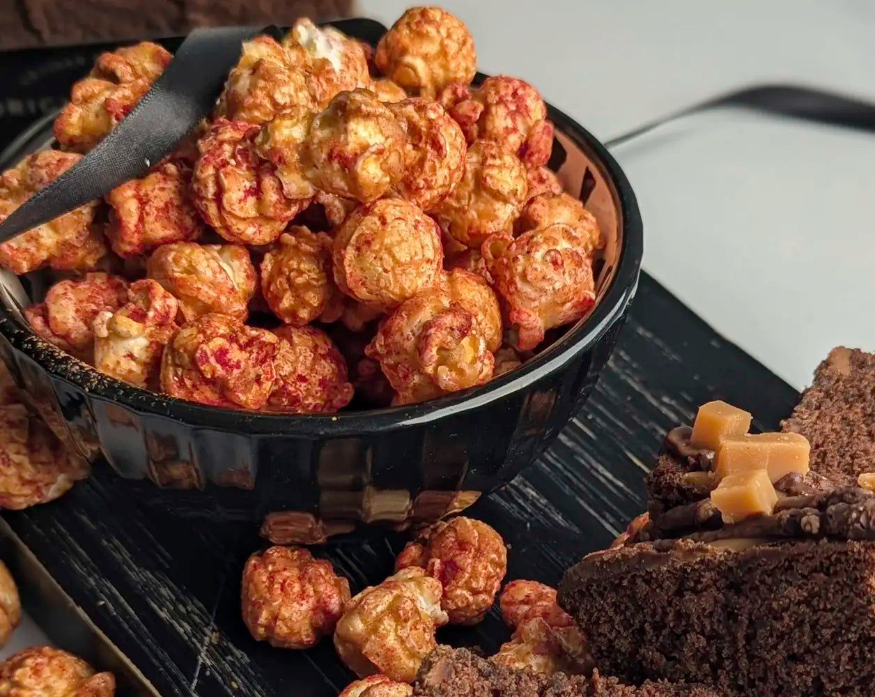 Black bowl filled with popcorn on a dark surface