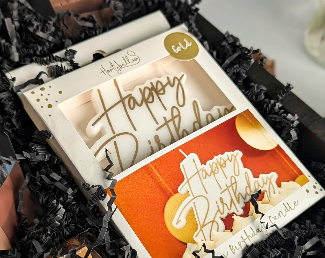 'Happy Birthday' candle in a box with black crinkled paper