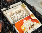 'Happy Birthday' candle in a box with black crinkled paper