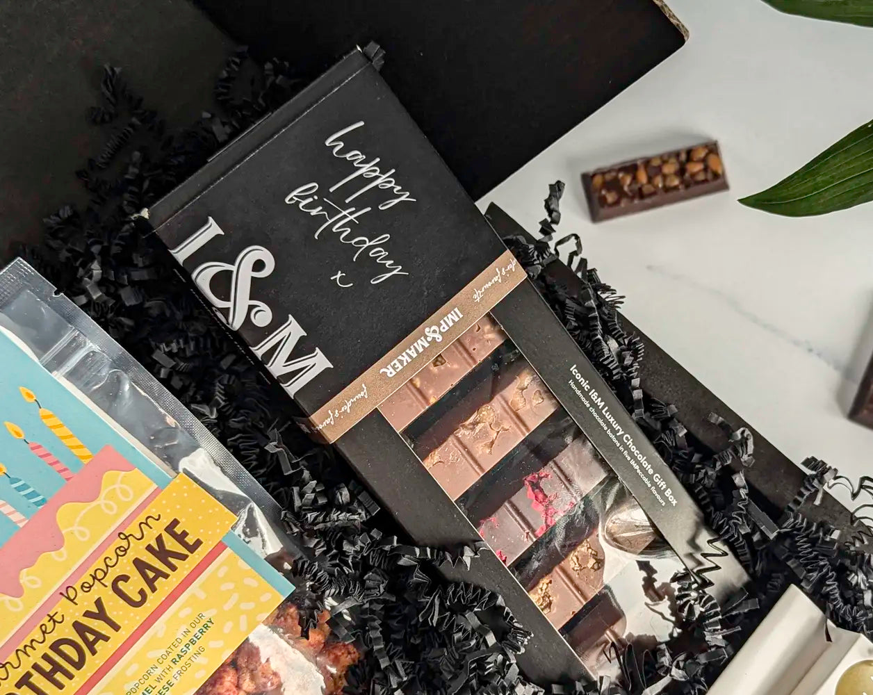 Chocolate gift set with 'Happy Birthday' message and birthday-themed packaging on a white surface.