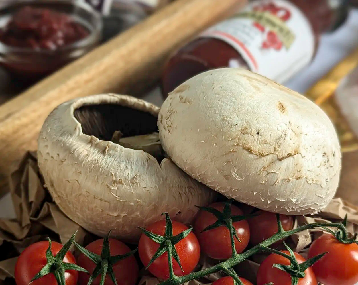Two large mushrooms and cherry tomatoes on a wooden surface with a blurred background