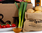 Spring onions propped against a luxury food hamper gift.