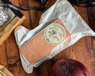 Block of Lincolnshire Red Cheese on a wooden surface with a visible brand label.