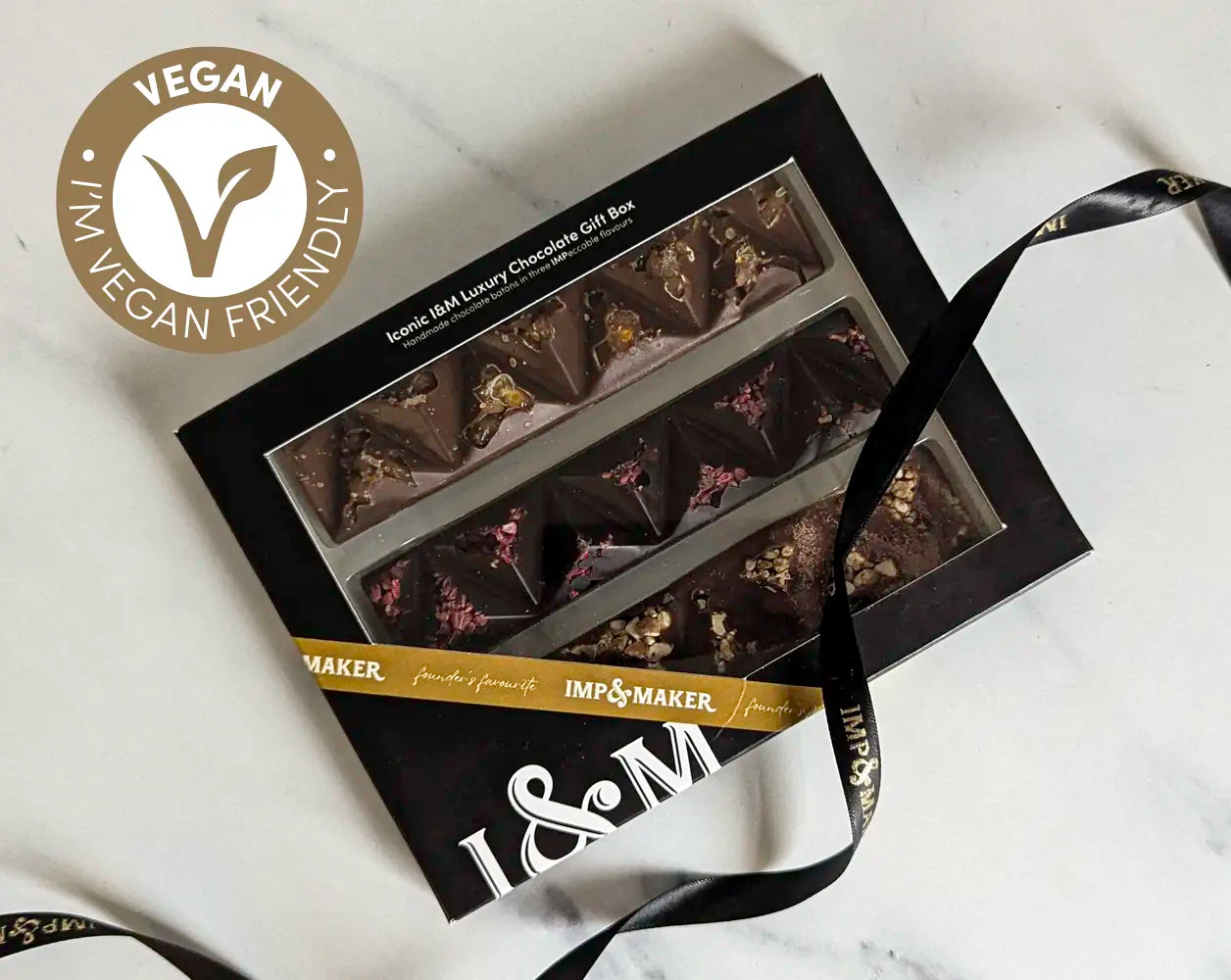 Box of chocolates with 'Vegan Friendly' label and 'IMP & MAKER' branding on a light background